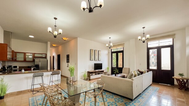 Una cocina moderna con comedor, una sala de estar con sofá y un amplio ventanal.