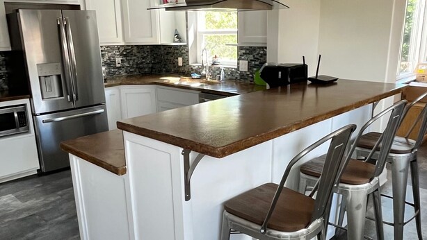 A modern kitchen with white cabinetry, stainless steel appliances, a large island with bar stools, and a view of the outdoors. -  Three bedroom home near the University of New Mexico and heart of Albuquerque (Albuquerque)