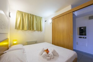 Ein Hotelzimmer mit einem Bett, einem Nachttisch mit Lampe, einem Holzschrank und einem an der Wand montierten Fernseher.