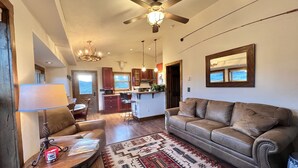A living room with a sofa, a coffee table, a rug, and a ceiling fan.