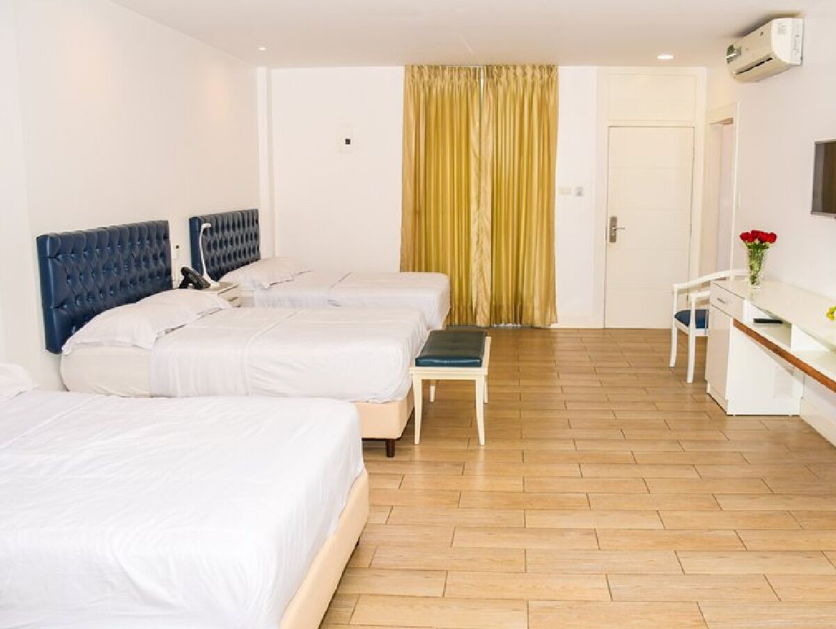 Una habitación de hotel con tres camas, un escritorio y una silla.