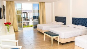 Habitación de hotel con dos camas, un escritorio, una silla y vistas a un balcón.