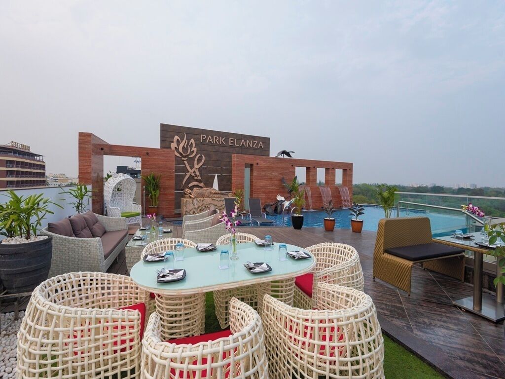 A rooftop bar with wicker furniture, a pool, and a sign reading "Park Elanza".
