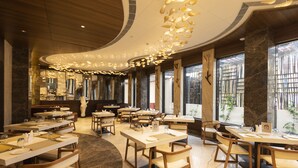 Un restaurante con varias mesas y sillas, ventanas amplias y un diseño moderno en el techo.
