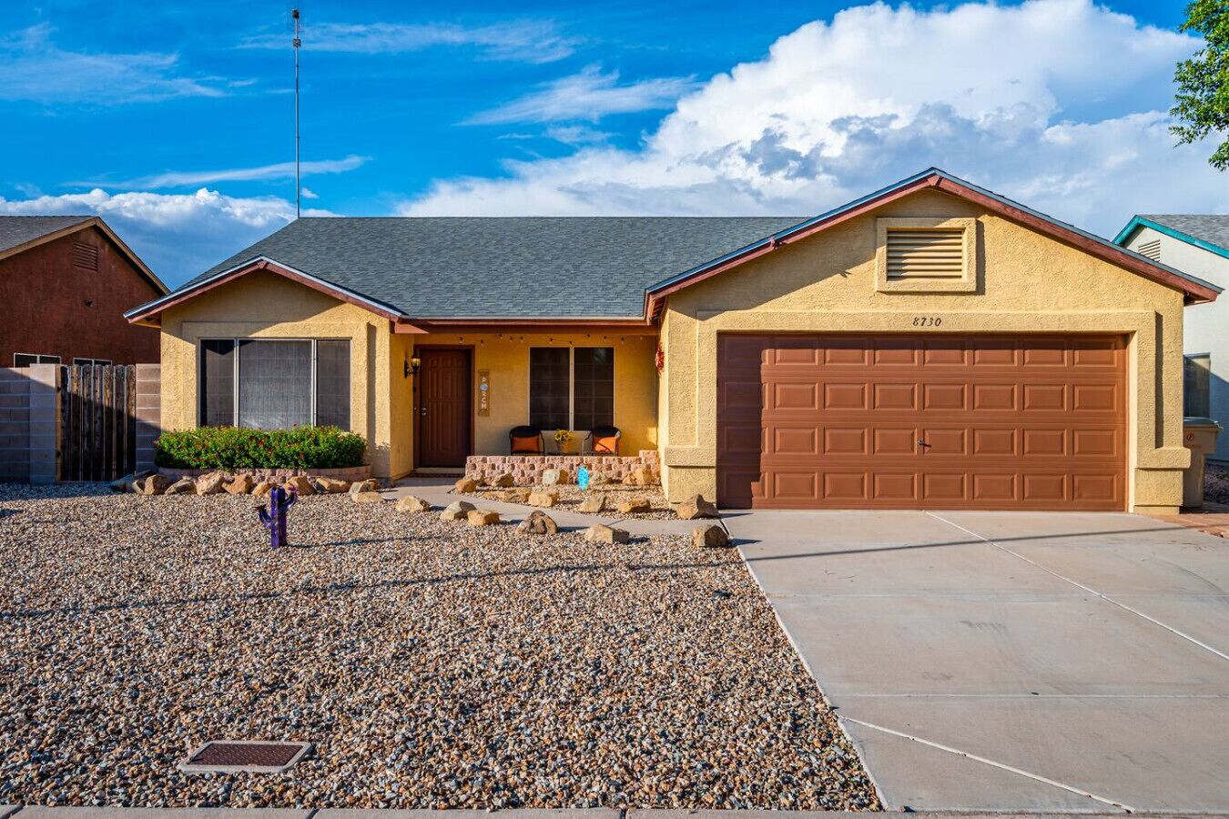 A single-story house with a garage, a front porch, and a gravel driveway.