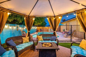 An outdoor patio with wicker furniture, a fire pit, and a pool in the background. - Walk 2 Stadium- Pool-Firepit-Pets ok (Glendale)