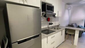 A compact kitchen with white cabinets, a stainless steel refrigerator, a microwave, and a sink. - 2Rcondo balcony Surrounded by history with Modern Amenities (Panama City)