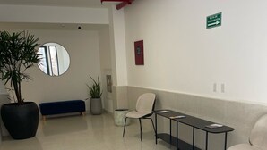 A spacious waiting area with a long bench, a round mirror, and a potted plant. - 2Rcondo balcony Surrounded by history with Modern Amenities (Panama City)