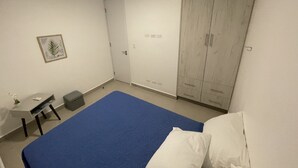 A bedroom with a bed, a wardrobe, a desk, and a chair. - 2Rcondo balcony Surrounded by history with Modern Amenities (Panama City)