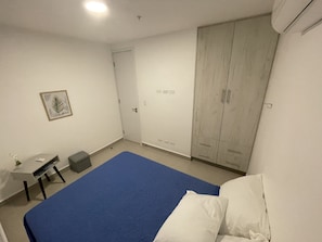 A bedroom with a bed, a wardrobe, a desk, and a chair.