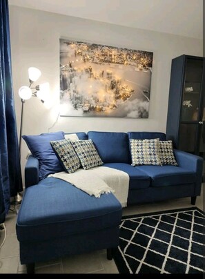Relax in this stylish living room with a blue sofa, cityscape artwork, and floor lamp.