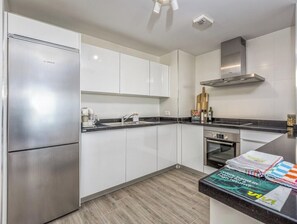 A modern kitchen with white cabinetry, stainless steel appliances, and a black countertop. - Casa Ferli | pool - sea view - garden (Marbella)