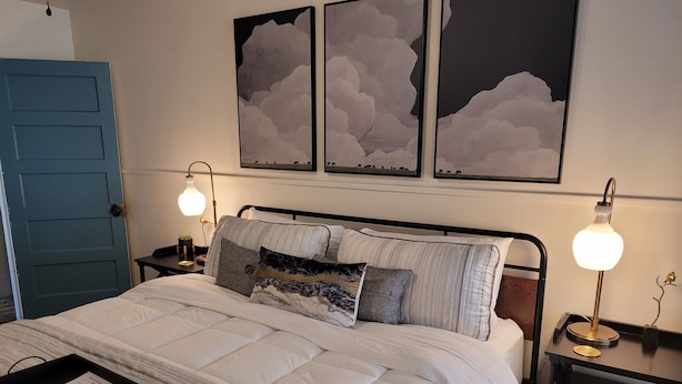 A neatly made bed with a black tray, two bedside tables with lamps, and artwork on the wall. - Mountainside Inn (Fort Davis)