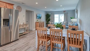 Una cocina moderna con un refrigerador de acero inoxidable, una mesa de comedor de madera con sillas y vistas al exterior.