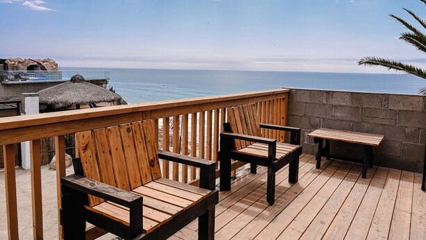 Eine Holzdar Terrasse mit Sitzgelegenheiten und Blick aufs Meer.
