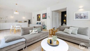 A modern living room with two grey sofas, a white coffee table, and a dining area with a white table and chairs. - Coolart Studios: Studio Two (Balnarring)