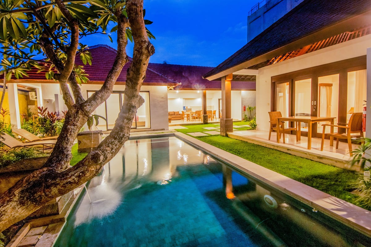 A pool area with a clear view of the surrounding patio and a building with a tiled roof.