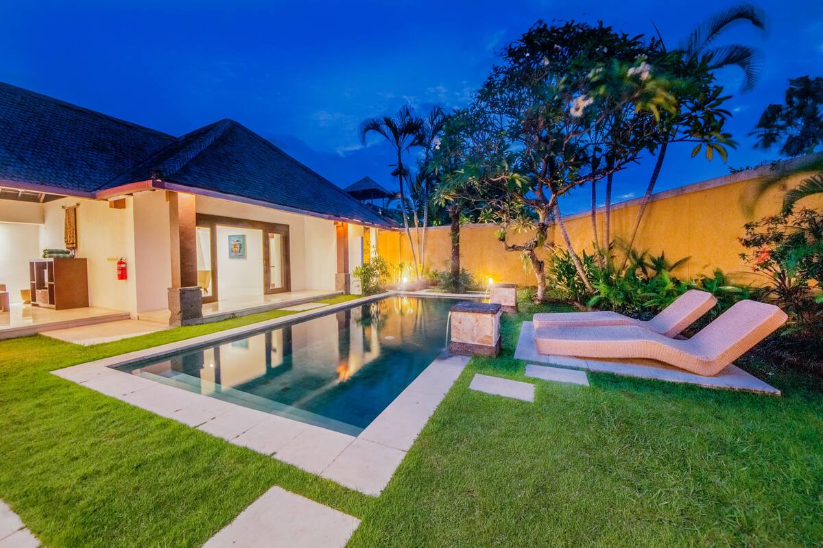 A modern house with a swimming pool, outdoor seating, and a well-maintained garden.