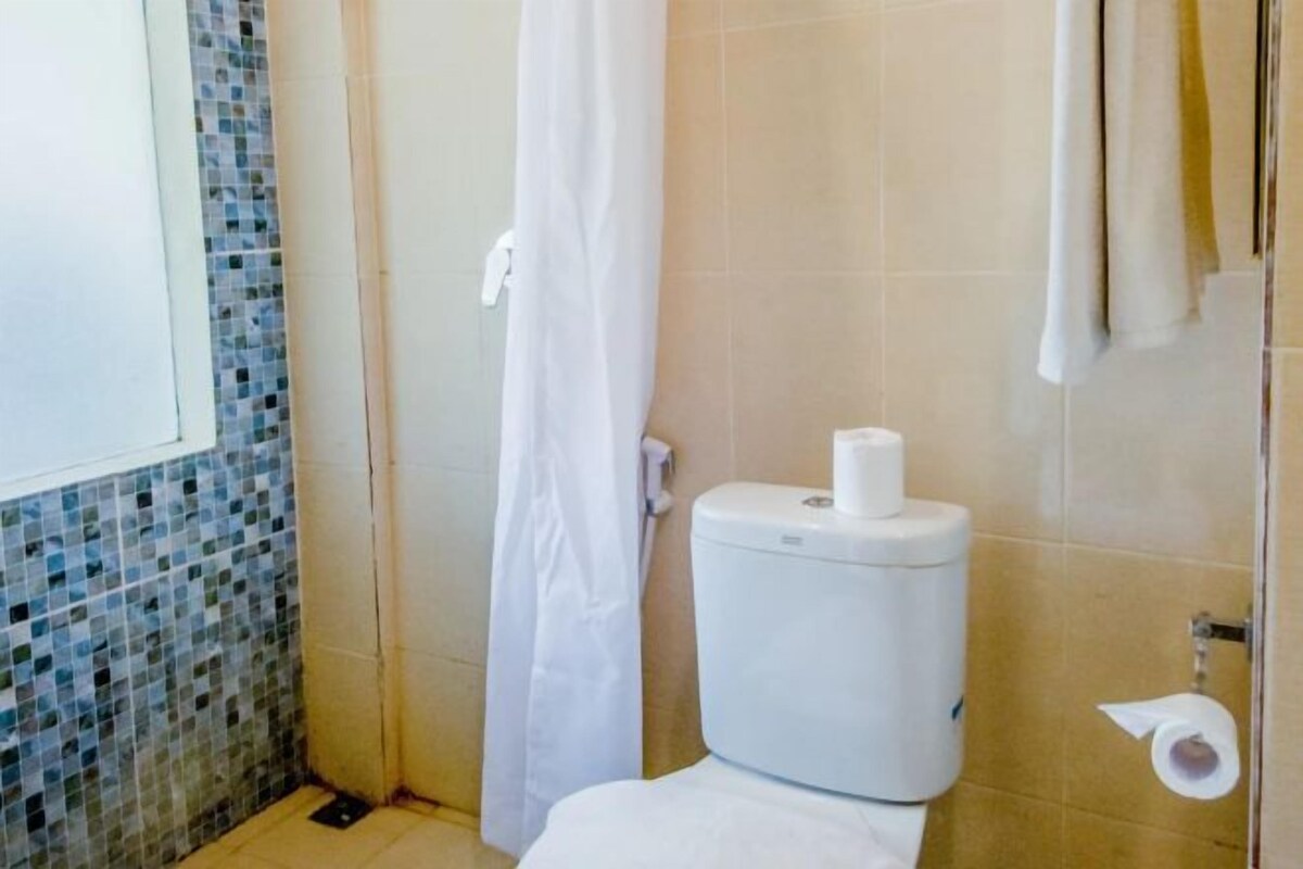 A bathroom with a toilet, a shower curtain, and a toilet paper holder.