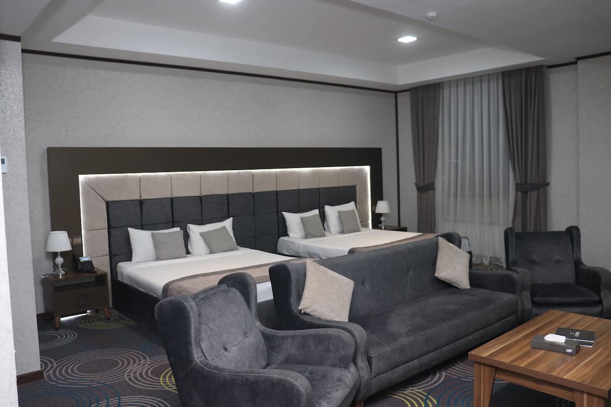 Une chambre d’hôtel avec deux lits, un canapé, une chaise et une petite table.