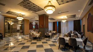 A hotel dining area with checkered flooring, multiple tables, and chairs. - Volga Hotel (Baku)