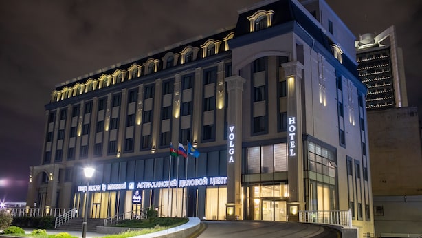 A hotel with a classic architectural design, featuring a prominent entrance and multiple flags. - Volga Hotel (Baku)