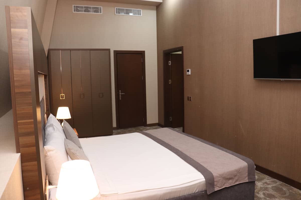 Une chambre d’hôtel avec un lit, un téléviseur fixé au mur et une armoire.