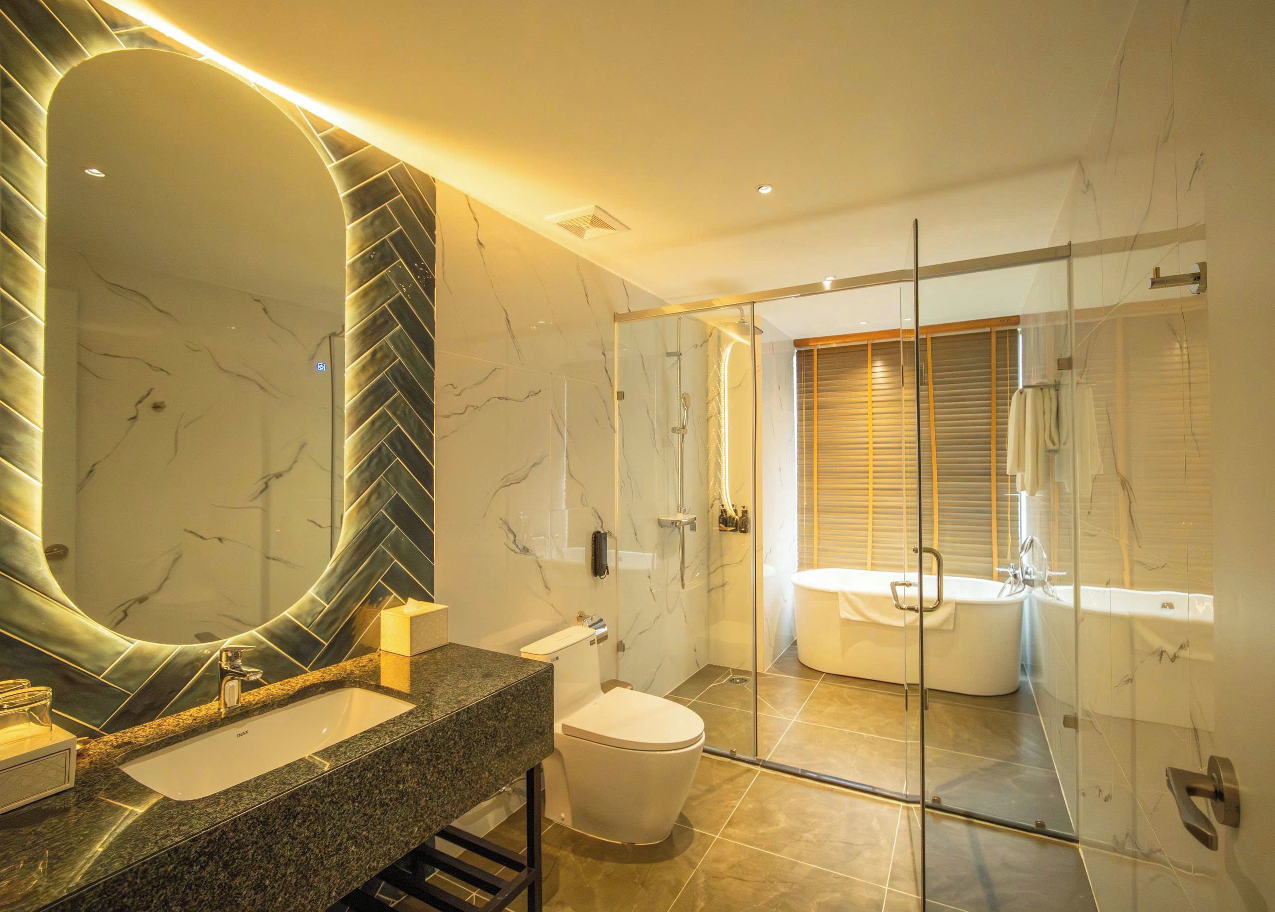 Un baño moderno con un espejo grande, una bañera y una zona de ducha.