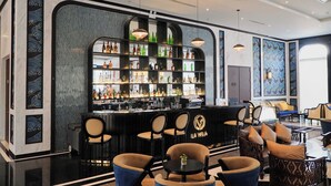 A bar area with a black counter, multiple shelves of bottles, and several chairs. - La Vela Hue Hotel (Hue)