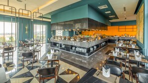 A modern restaurant with a bar area, high ceilings, and a view of the city. - La Vela Hue Hotel (Hue)