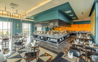 A modern restaurant with a bar area, high ceilings, and a view of the city.