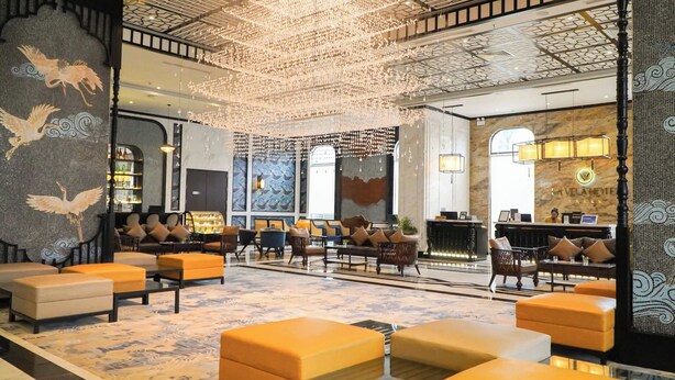 A spacious lobby with a high ceiling, ornate wall decorations, and a variety of seating arrangements. - La Vela Hue Hotel (Hue)