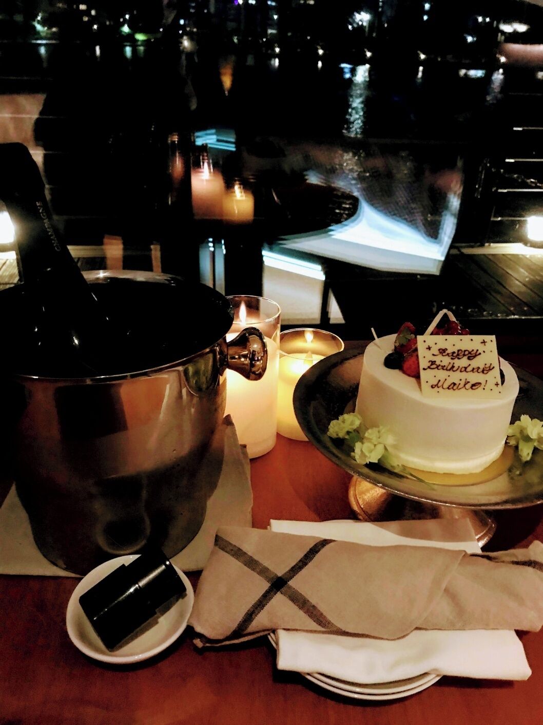 A table with a cake, candles, and a bottle of champagne.