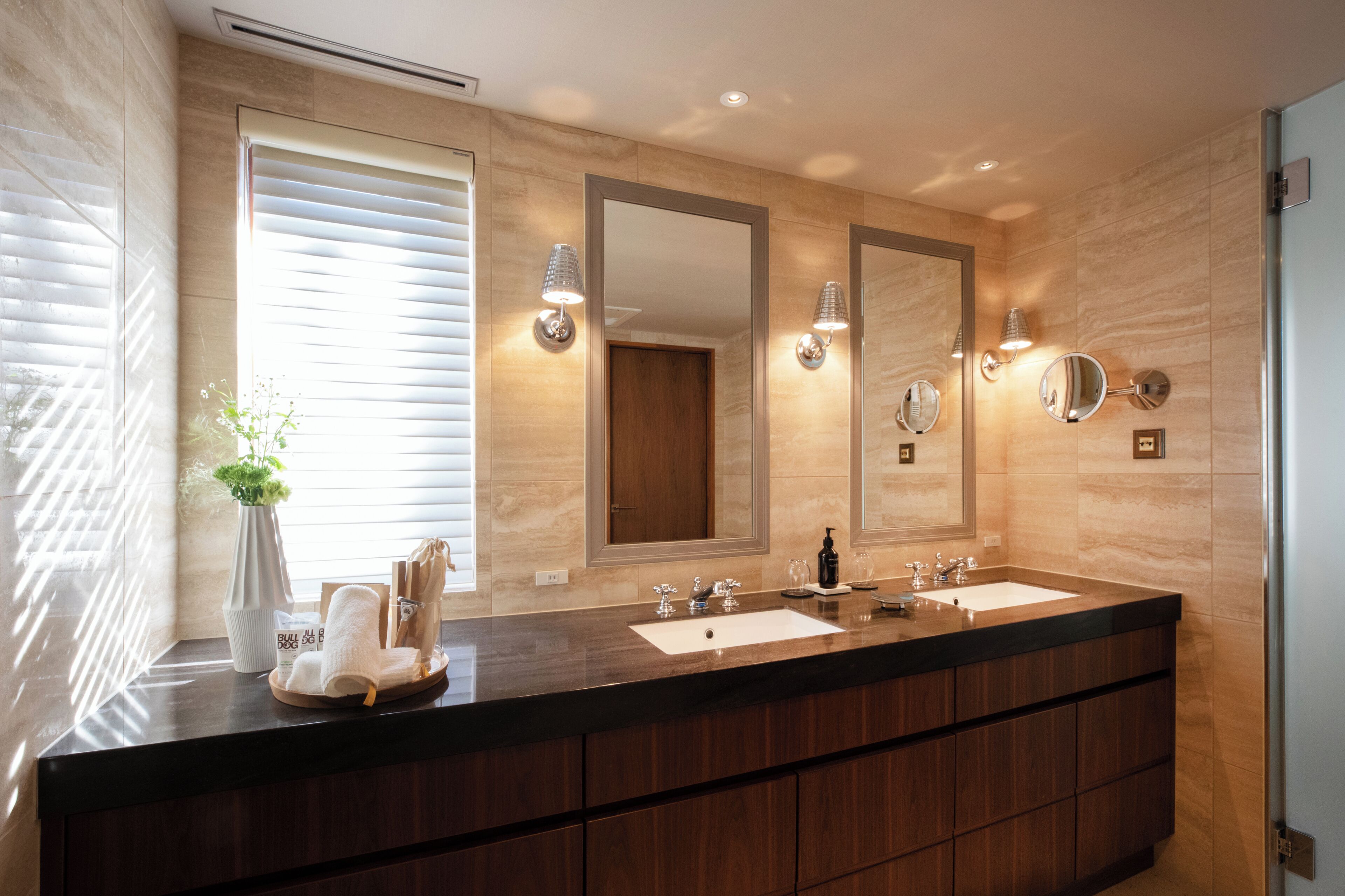 A modern bathroom with two sinks, large mirrors, and wall-mounted lighting.