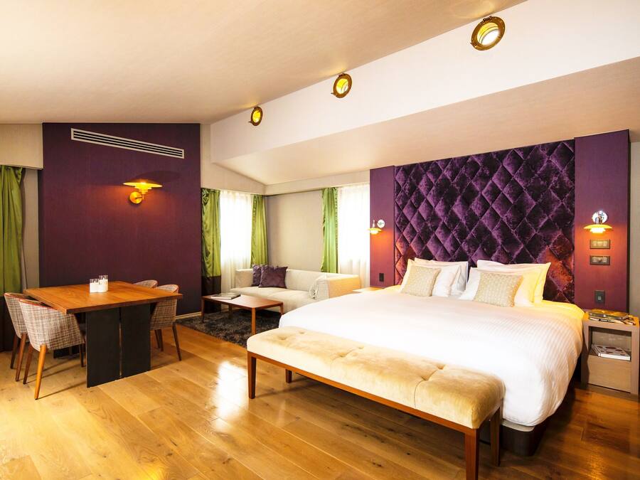 Una habitación de hotel moderna con una cama grande, un escritorio y un sofá.