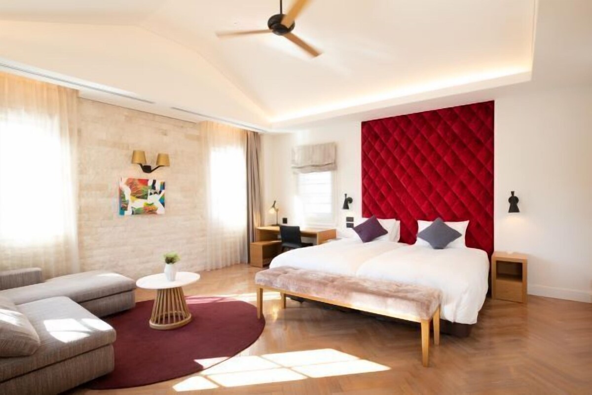 Una camera da letto moderna con un letto grande, una scrivania, un divano e una ventola a soffitto.