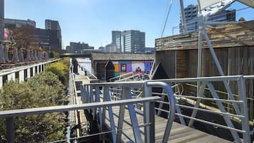 Eine Fußgängerbrücke mit Metallgeländern und Holzdielen, die auf einen Fluss mit Booten blickt.