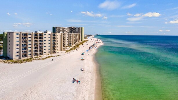 A beachfront hotel with multiple floors, a sandy beach, and a clear blue ocean. - Pinnacle Port A533 (Panama City Beach)