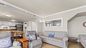A compact living space with a kitchenette, a striped sofa, and a dining area. - Pinnacle Port A533 (Panama City Beach)