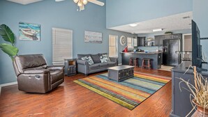 A living room with a leather chair, a gray sofa, a colorful striped rug, and a ceiling fan. - Fun and Sun Vacation Townhome (Panama City Beach)