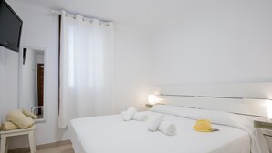 A hotel room with a bed, a nightstand, a TV, and a window with a curtain.