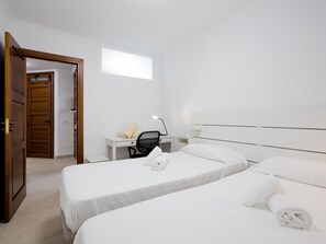 Ett hotellrum med två sängar, ett skrivbord med en stol, en telefon och ett fönster.