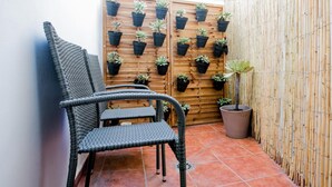 Une chaise en osier, un mur en bambou et une porte en bois ornée de plantes en pot.