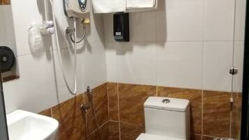 A bathroom with a toilet, a shower, and a sink.