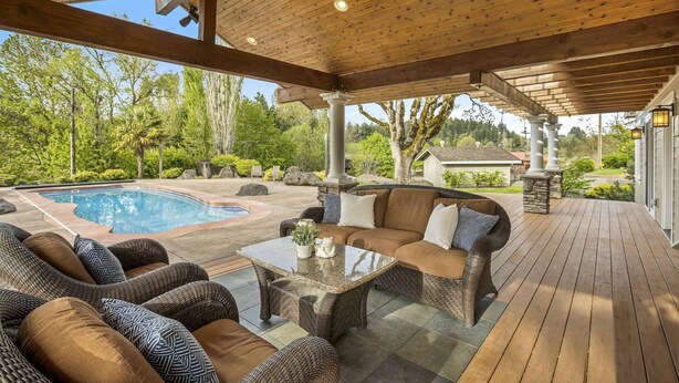 Eine Terrasse im Freien mit Pool, Korbmöbeln und einer Pergola.