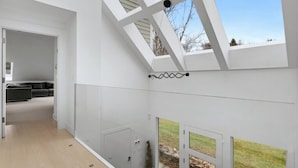 A modern interior with a skylight, a view of the outdoors, and a grey sofa in the background.