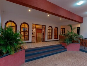 A hotel entrance with arched windows, a staircase, and potted plants. - Jasminn Villas South Goa (Betalbatim)