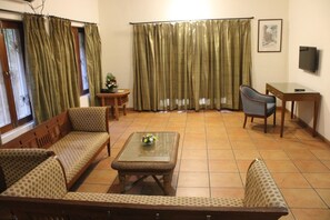 A living room with a sofa, armchair, and a small table with a vase. - Jasminn Villas South Goa (Betalbatim)