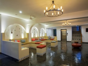 A spacious lobby with a wet floor, seating areas with cushions, a chandelier, and an elevator. - Jasminn Villas South Goa (Betalbatim)