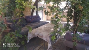 An outdoor seating area with a sofa and a table, surrounded by greenery and trees. - Appartement Quartier Calme (Perpignan)